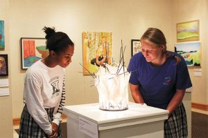 WORK OF ART Juniors Sydney Thomas and Jessica Savage examine a sculpture by Ashley Payne Bahun ‘05 made of steel, yarn and light. PHOTO BY TIFFANY PON