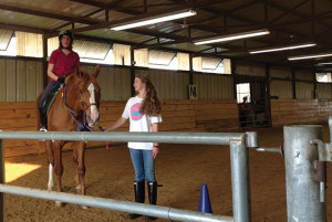 TAKING THE REINS Sophomore Raney Sachs leads a rider in the indoor arena at Equest. Photo taken by Carol Battalora