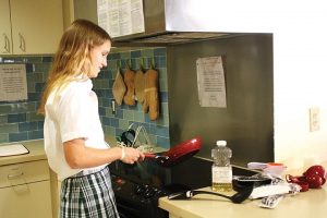 MASTER CHEF  Junior Elizabeth Michel demonstrates her cooking skills in the Tarry House kitchen. PHOTO BY AUDREY KIM