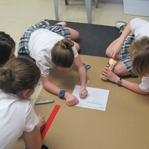 BOAT BUILDING (L to R) Seventh graders Parker Waters, Addy Sykes, Audrey Martin and Swiler Boyd sketch the dimensions of their boat in order to assemble their canoe. Photo by Claire Fletcher