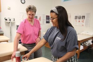 LEARNING FROM THE COACH Senior Kennedy Williams receives tips about taping and wrapping ankles from Head Athletic Trainer Jeanne Olson. Credit: Claire Fletcher