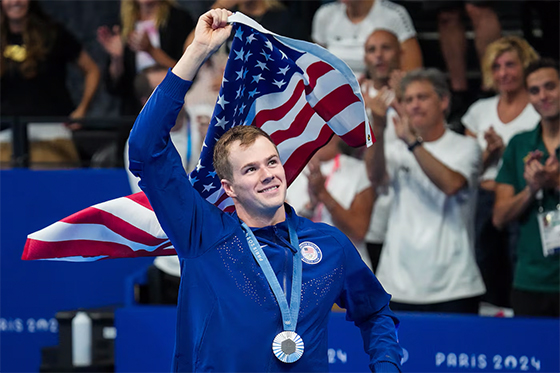 American Swimmer Nic Fink parades around the París La Défense Arena after winning a silver medal in the men's 100 meter breast stroke. Due to insufficient funding from his sport, Fink, like several other Olympic athletes, works a job in addition his athletic training. 